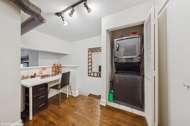 interior space with rail lighting, stacked washer / drying machine, and dark hardwood / wood-style flooring