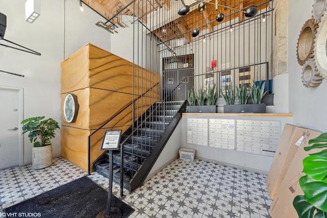 stairway featuring a towering ceiling and mail boxes