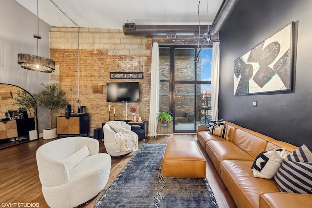 living room with brick wall and dark hardwood / wood-style floors