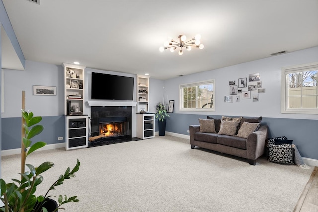 living room with an inviting chandelier, carpet flooring, built in shelves, and a wealth of natural light