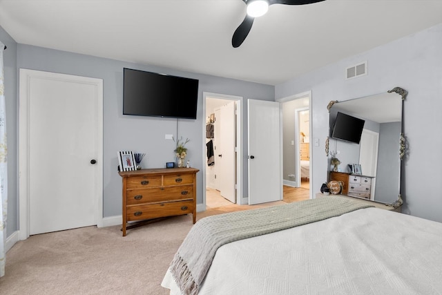 bedroom with ensuite bath, light colored carpet, and ceiling fan