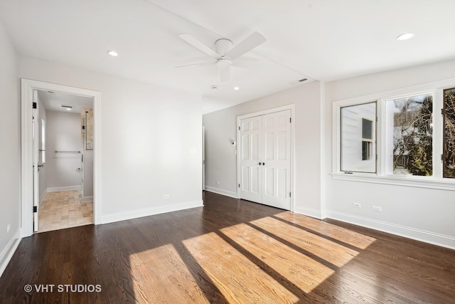 unfurnished bedroom featuring dark wood-type flooring, ceiling fan, connected bathroom, and a closet