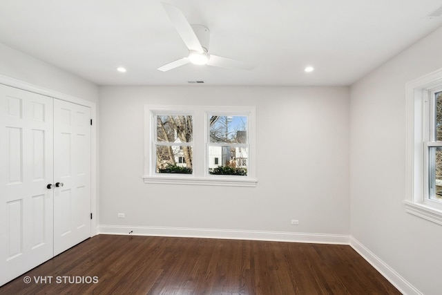 unfurnished bedroom with multiple windows, dark hardwood / wood-style flooring, a closet, and ceiling fan