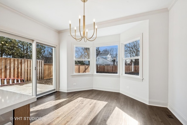 unfurnished dining area featuring ornamental molding, plenty of natural light, dark hardwood / wood-style floors, and a notable chandelier