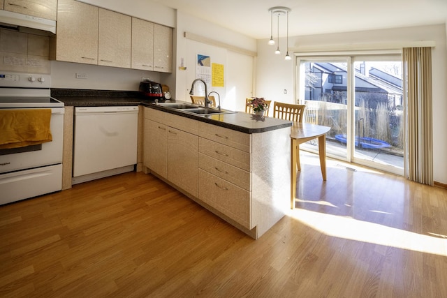 kitchen featuring pendant lighting, sink, white appliances, light hardwood / wood-style floors, and kitchen peninsula