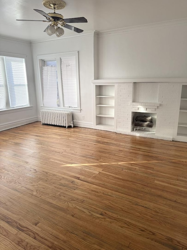 unfurnished living room featuring a fireplace, radiator heating unit, ornamental molding, and hardwood / wood-style floors