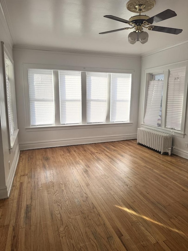 unfurnished sunroom featuring plenty of natural light, radiator, and ceiling fan