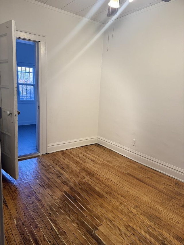 empty room with hardwood / wood-style floors and ornamental molding