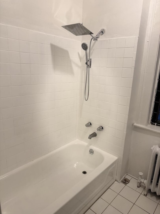 bathroom featuring tile patterned floors, radiator heating unit, and tiled shower / bath