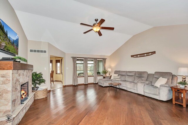 living room with dark hardwood / wood-style flooring, a fireplace, vaulted ceiling, and ceiling fan