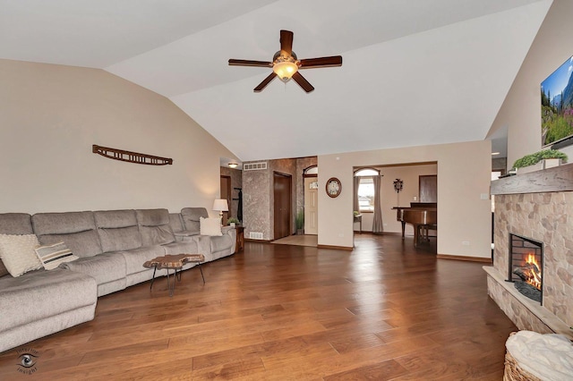 living room with ceiling fan, high vaulted ceiling, a stone fireplace, and hardwood / wood-style floors