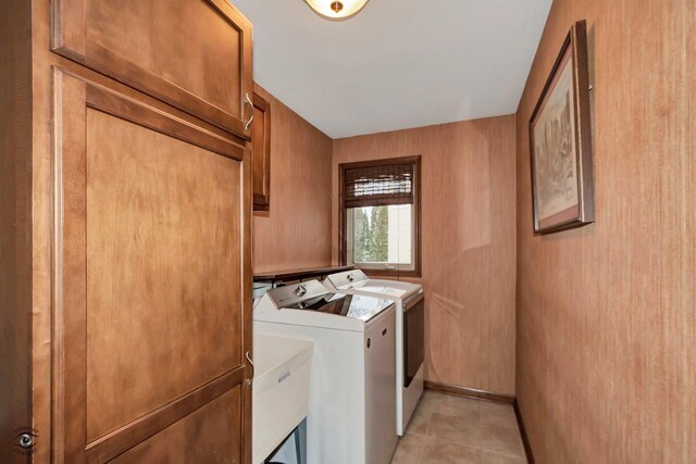 clothes washing area with separate washer and dryer, light tile patterned floors, and cabinets