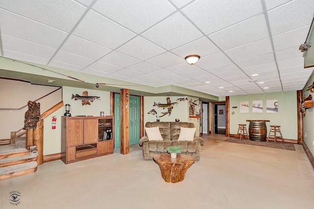 living area featuring a paneled ceiling and concrete floors