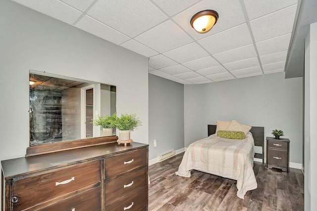 bedroom featuring a drop ceiling, a baseboard radiator, and dark hardwood / wood-style floors