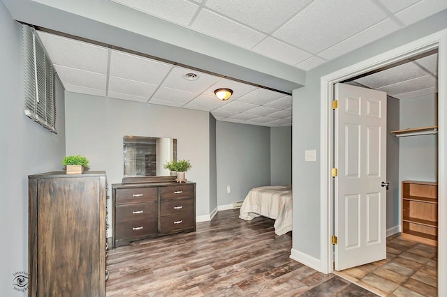 bedroom with a baseboard heating unit, a paneled ceiling, and wood-type flooring