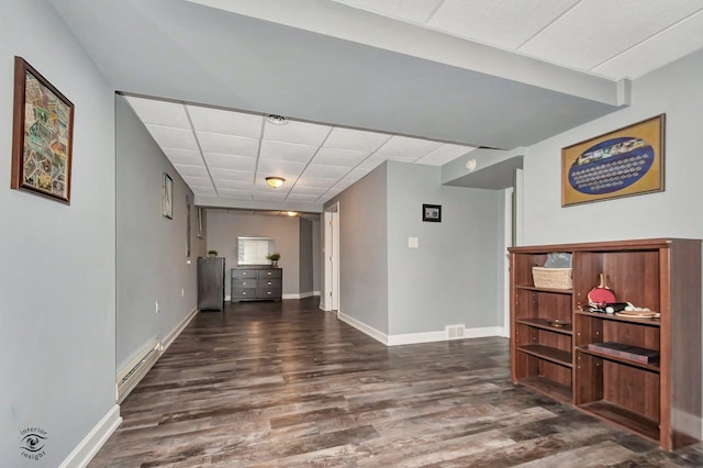 interior space featuring a baseboard heating unit, dark hardwood / wood-style floors, and a paneled ceiling