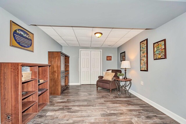 sitting room featuring hardwood / wood-style floors and a drop ceiling