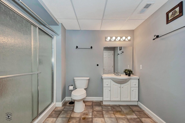 bathroom with a shower with door, vanity, a paneled ceiling, and toilet