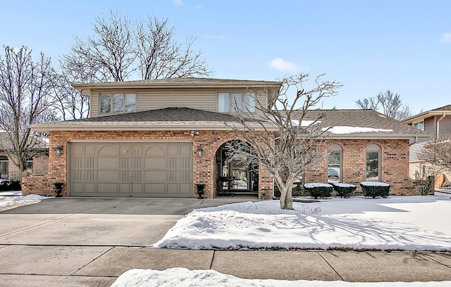 traditional-style home featuring driveway, an attached garage, roof with shingles, and brick siding