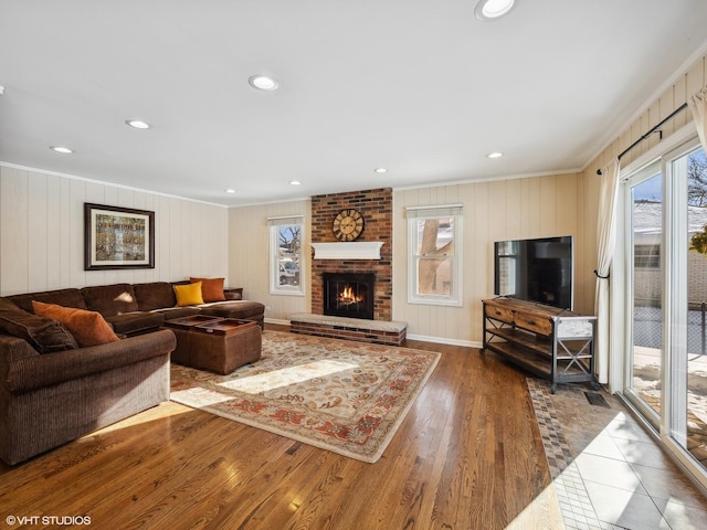 living room with a healthy amount of sunlight, crown molding, a fireplace, and wood finished floors