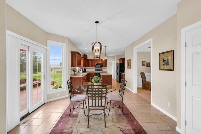 dining area with a chandelier, baseboards, and light tile patterned flooring