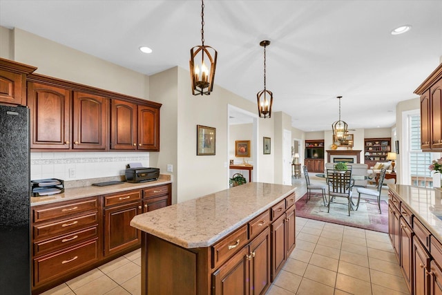 kitchen with light stone counters, decorative backsplash, hanging light fixtures, and freestanding refrigerator