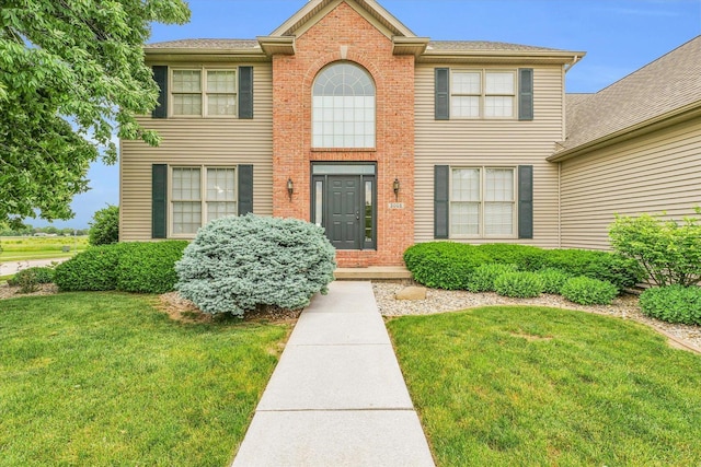 view of front facade featuring brick siding and a front yard