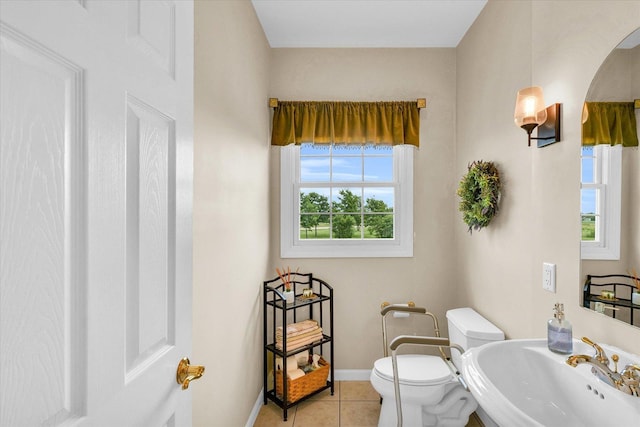 bathroom with a sink, baseboards, toilet, and tile patterned floors