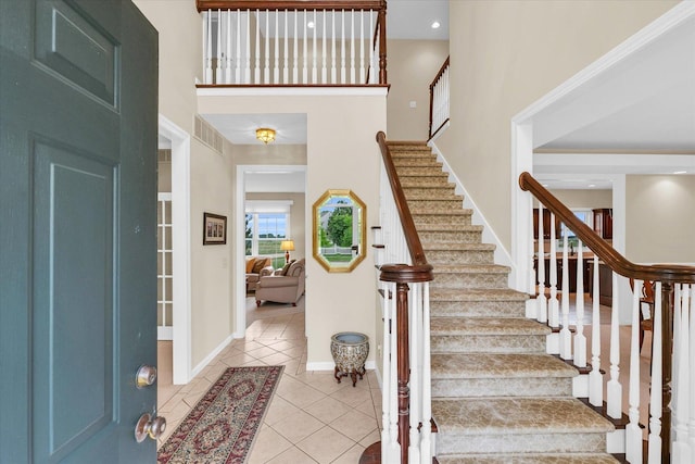 foyer featuring tile patterned flooring, a high ceiling, and baseboards