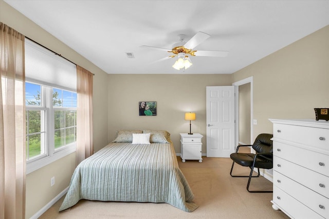 bedroom with visible vents, light colored carpet, a ceiling fan, and baseboards