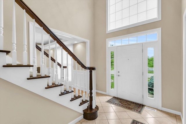 entrance foyer featuring light tile patterned floors, visible vents, baseboards, and a towering ceiling