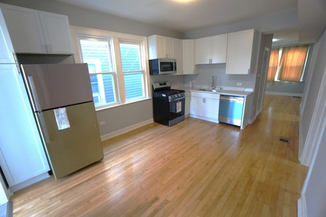 kitchen featuring white cabinetry, appliances with stainless steel finishes, sink, and light wood-type flooring