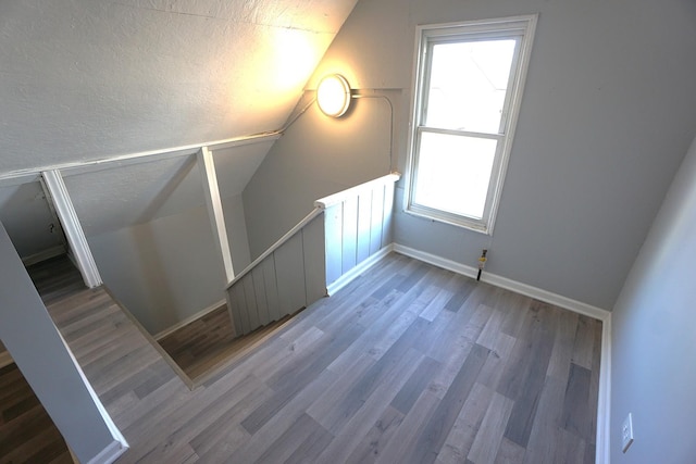 bonus room with hardwood / wood-style flooring and vaulted ceiling