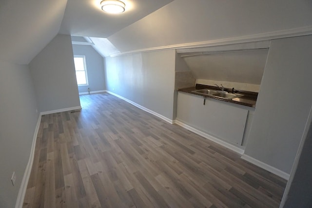 additional living space with sink, hardwood / wood-style flooring, and vaulted ceiling