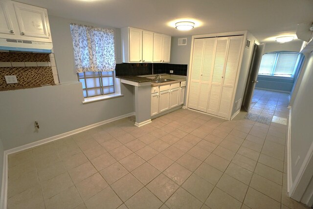 kitchen with light tile patterned flooring, sink, decorative backsplash, and white cabinets