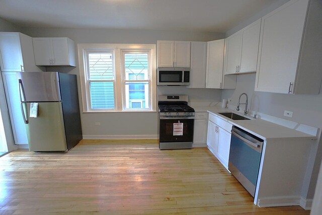 kitchen with white cabinetry, stainless steel appliances, light hardwood / wood-style floors, and sink