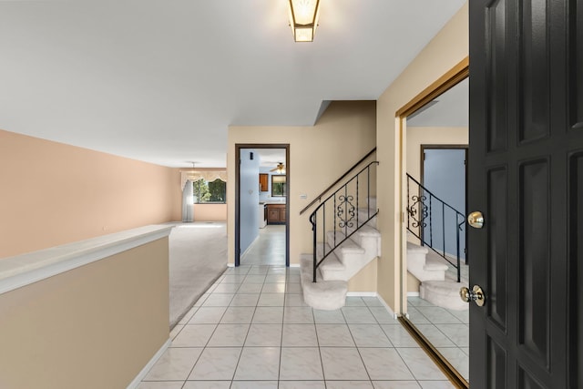 foyer entrance with light carpet, stairway, baseboards, and light tile patterned floors