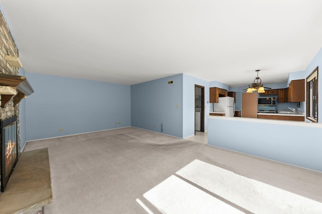 unfurnished living room featuring a brick fireplace, light colored carpet, a notable chandelier, and a sink