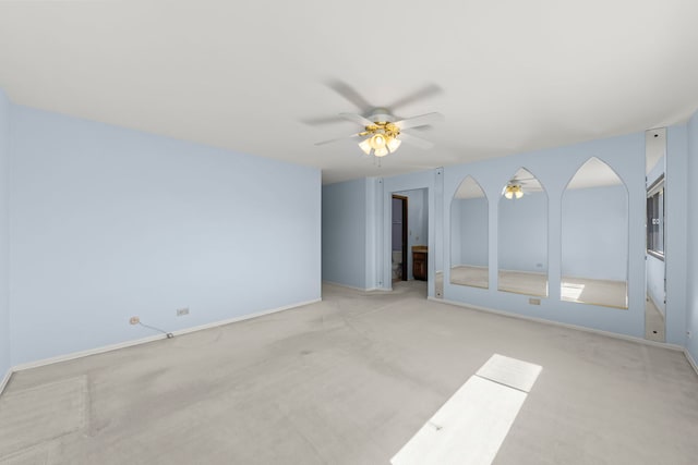 empty room featuring a ceiling fan, carpet, and baseboards