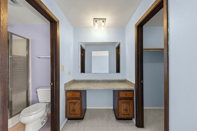 bathroom with a stall shower, baseboards, vanity, and toilet