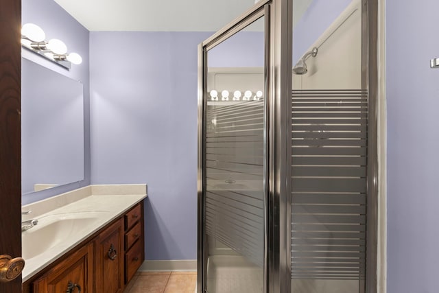 bathroom with baseboards, a shower stall, vanity, and tile patterned floors