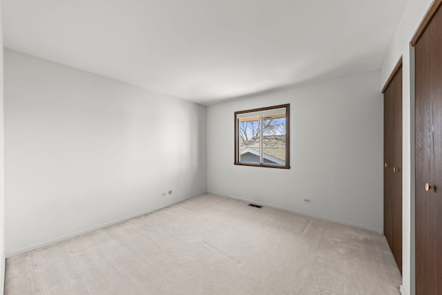 unfurnished bedroom featuring a closet, light colored carpet, visible vents, and baseboards