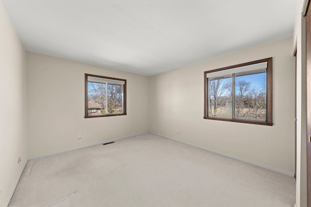 carpeted spare room featuring visible vents and baseboards