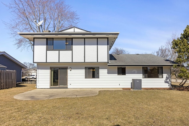 rear view of property featuring roof with shingles, a patio area, a lawn, and fence