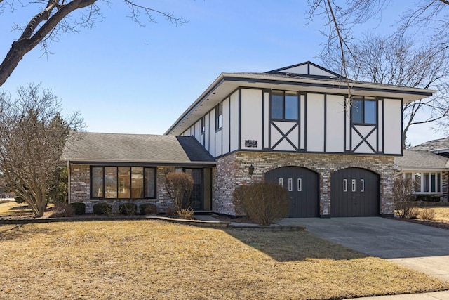 english style home featuring driveway, a front yard, a garage, and brick siding