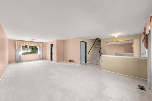 carpeted spare room featuring stairs and visible vents