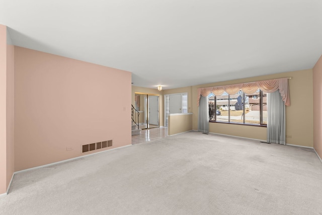 spare room with visible vents, light carpet, baseboards, and stairs