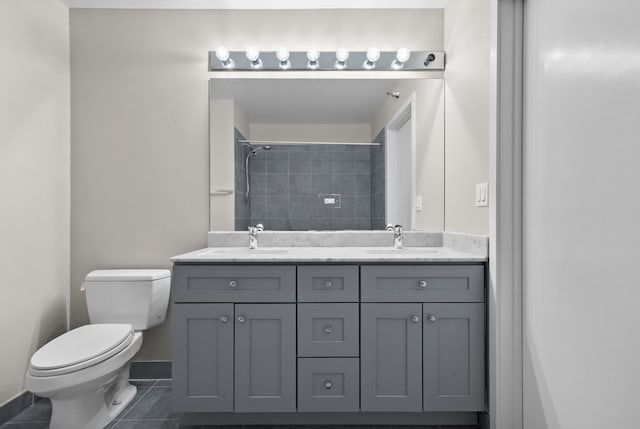 bathroom with vanity, tile patterned floors, toilet, and a tile shower