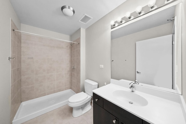 bathroom with tile patterned floors, vanity, toilet, and a tile shower