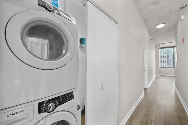 laundry room featuring stacked washer / drying machine and hardwood / wood-style floors